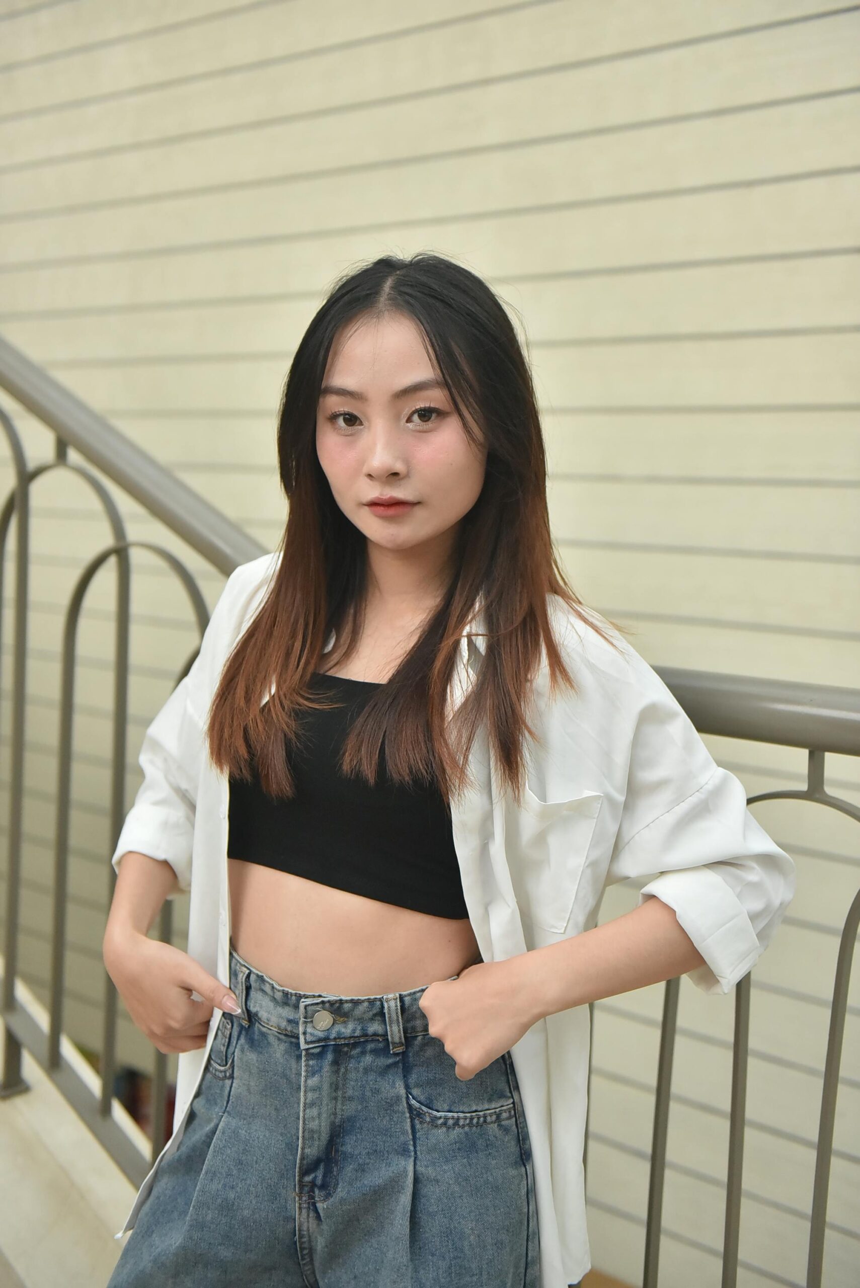 Home Confident young woman poses on staircase wearing casual attire. Urban setting, stylish outfit, modern vibe.